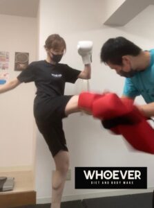 パーソナルジムでトレーナーとキックボクシングエクササイズをする女性
